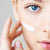 una mujer de ojos azules se aplica en la cara la crema rejuvenecedora orgánica IUM 